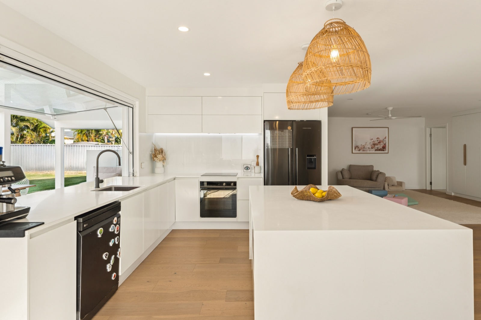 White kitchen with rattan pendants and stone island